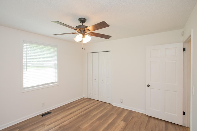 unfurnished bedroom with ceiling fan, a closet, and hardwood / wood-style floors