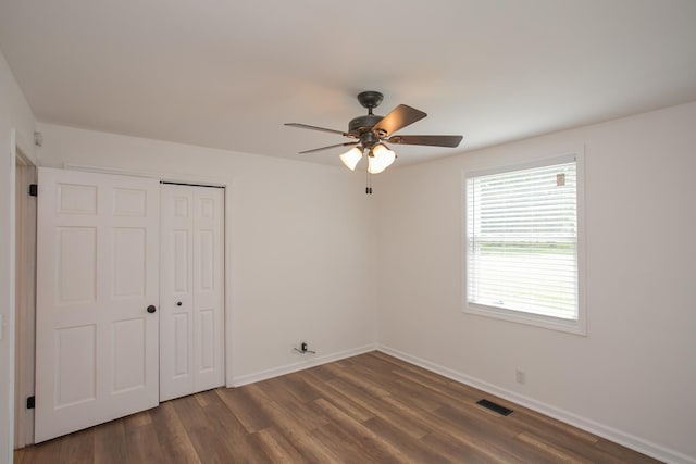 unfurnished bedroom with ceiling fan, a closet, and dark hardwood / wood-style flooring