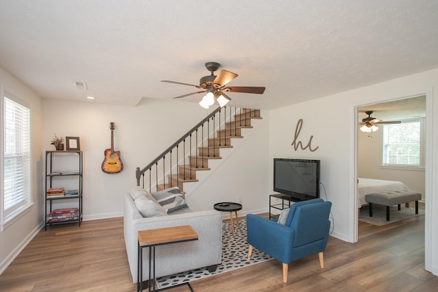 living room with a textured ceiling, ceiling fan, plenty of natural light, and wood-type flooring