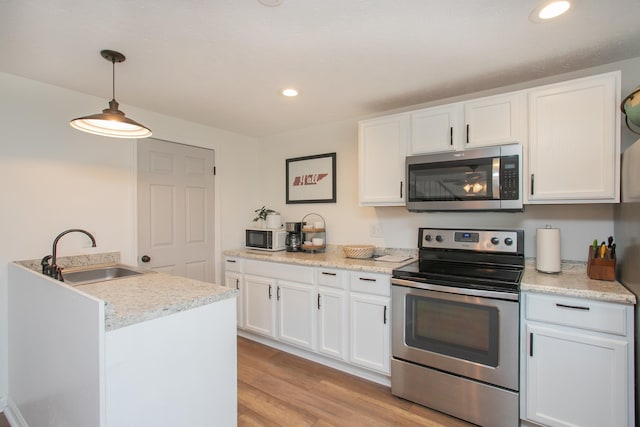 kitchen with sink, hanging light fixtures, light wood-type flooring, stainless steel appliances, and white cabinets