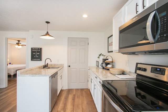 kitchen with white cabinetry, appliances with stainless steel finishes, light wood-type flooring, pendant lighting, and sink