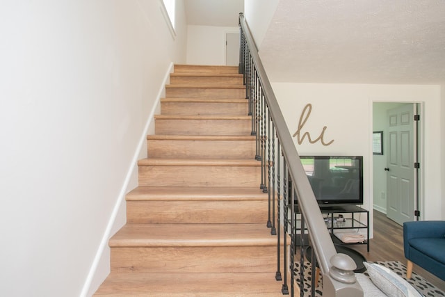 stairs featuring a textured ceiling and hardwood / wood-style floors