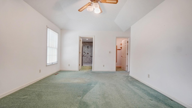 unfurnished bedroom featuring connected bathroom, ceiling fan, light colored carpet, vaulted ceiling, and a walk in closet