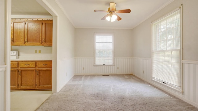 unfurnished dining area with ceiling fan, light carpet, and ornamental molding