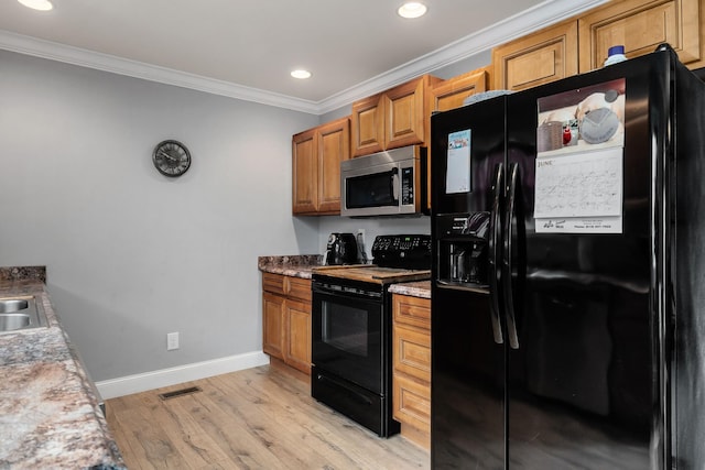 kitchen with light stone countertops, ornamental molding, sink, black appliances, and light hardwood / wood-style floors