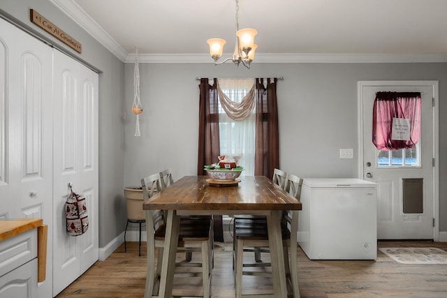 dining room with wood-type flooring, ornamental molding, and an inviting chandelier