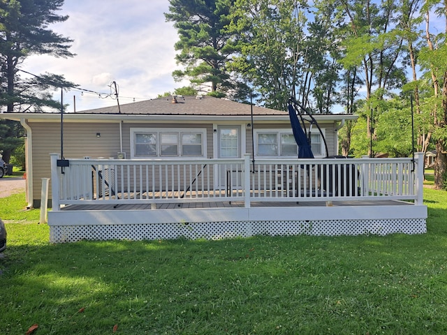 rear view of house featuring a wooden deck and a lawn