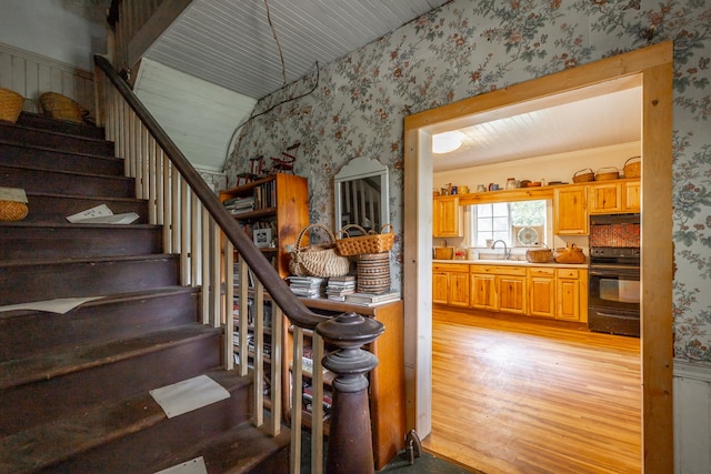 stairway featuring crown molding, sink, and wood-type flooring