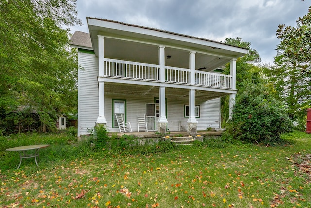 view of front of home with a balcony, covered porch, and a front yard