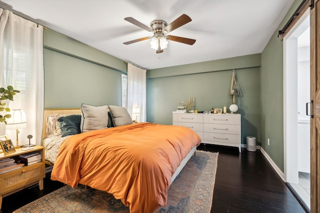 bedroom with ceiling fan, dark wood-type flooring, and a barn door