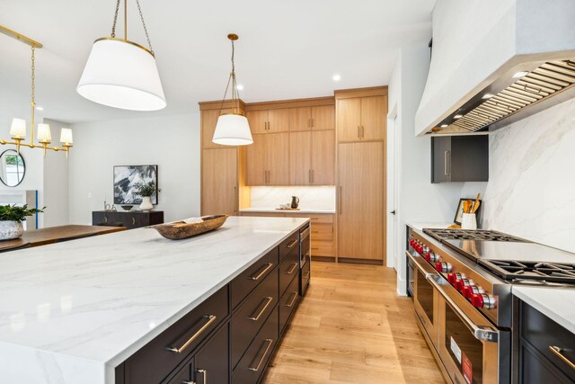 kitchen with double oven range, light hardwood / wood-style flooring, light stone counters, a center island, and custom exhaust hood