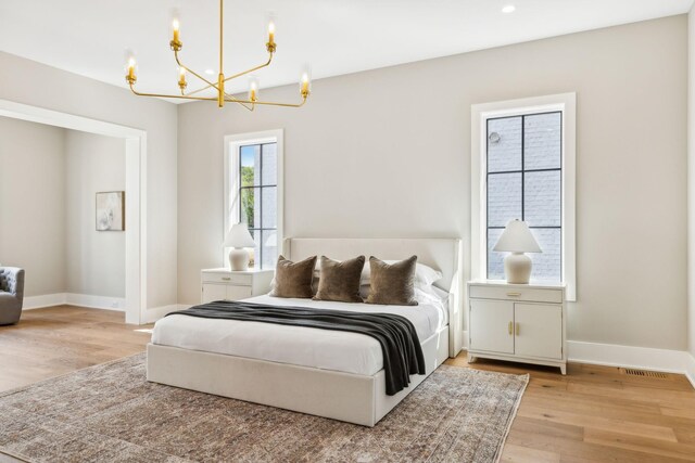 bedroom with light hardwood / wood-style floors and a notable chandelier