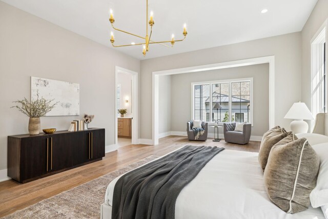 bedroom with connected bathroom, light hardwood / wood-style floors, and a chandelier