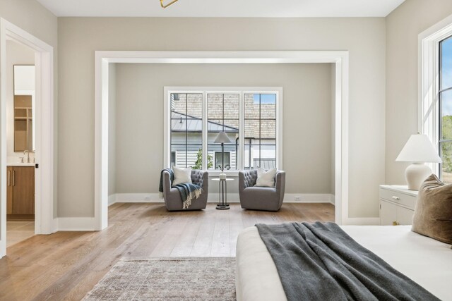 bedroom featuring ensuite bath and light wood-type flooring