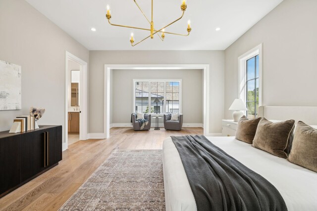 bedroom featuring light hardwood / wood-style floors, ensuite bathroom, and a chandelier