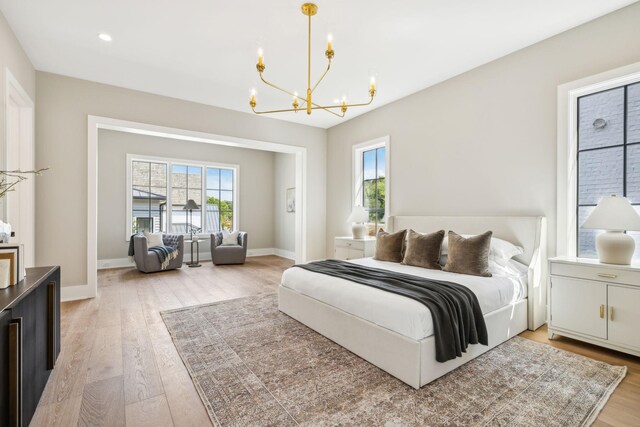 bedroom featuring light hardwood / wood-style floors, a chandelier, and multiple windows