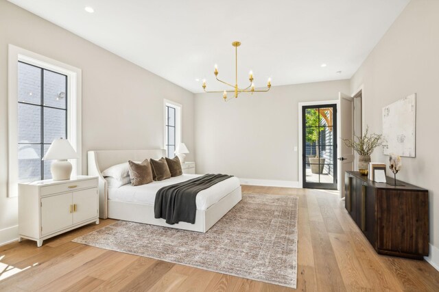 bedroom with a notable chandelier, light hardwood / wood-style flooring, and access to exterior