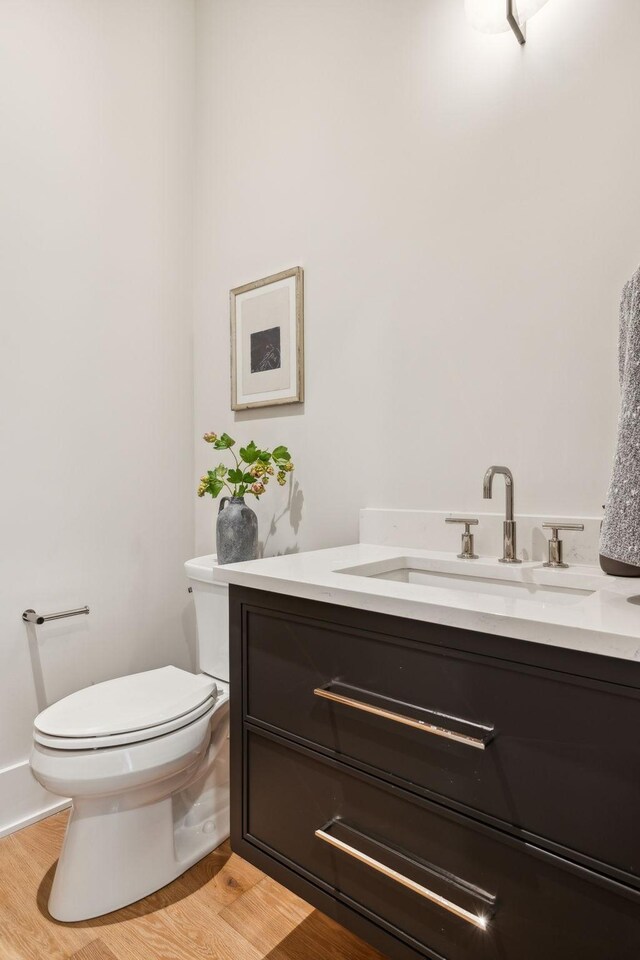 bathroom with wood-type flooring, toilet, and vanity