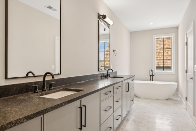 bathroom featuring tile patterned floors, a tub to relax in, and vanity