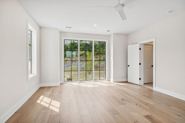 empty room with a wealth of natural light, ceiling fan, and light wood-type flooring