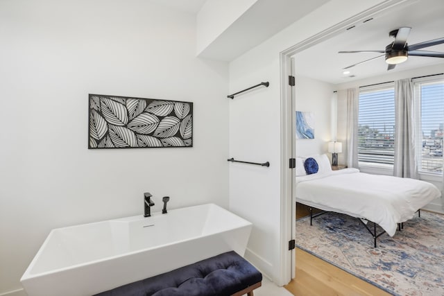 bathroom with ceiling fan, wood-type flooring, and a tub