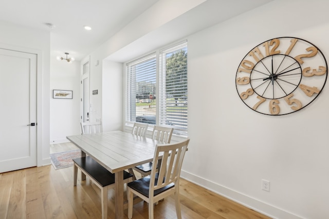 dining space with light hardwood / wood-style floors and a notable chandelier