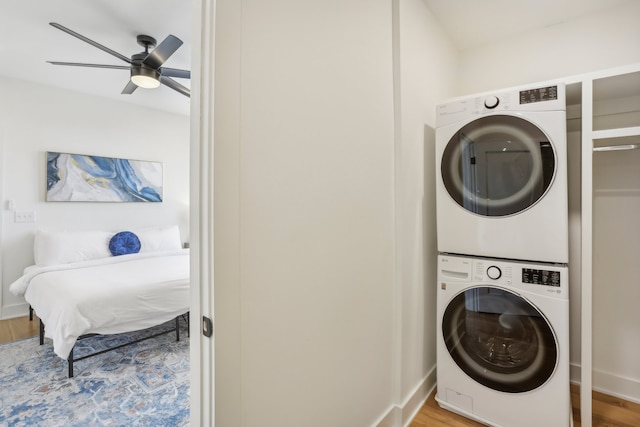 laundry room featuring ceiling fan, stacked washing maching and dryer, and light wood-type flooring