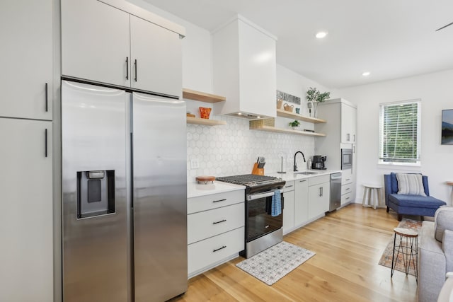 kitchen with tasteful backsplash, sink, white cabinets, custom exhaust hood, and stainless steel appliances