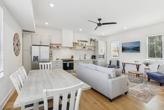 living room featuring ceiling fan, sink, and light hardwood / wood-style flooring