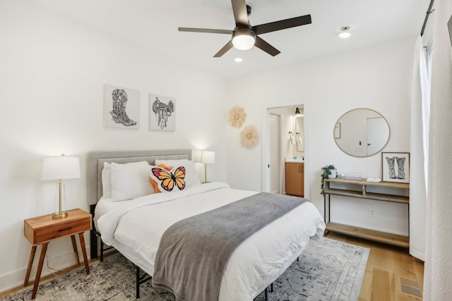 bedroom featuring connected bathroom, ceiling fan, and light wood-type flooring