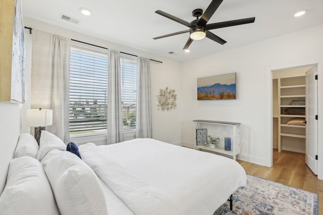 bedroom with ceiling fan, a spacious closet, and light wood-type flooring