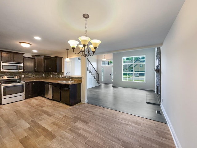 kitchen featuring sink, decorative light fixtures, appliances with stainless steel finishes, a notable chandelier, and dark brown cabinetry