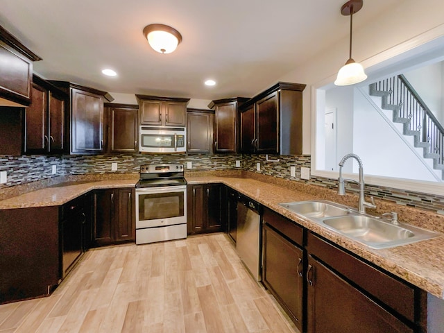 kitchen featuring pendant lighting, sink, light hardwood / wood-style flooring, tasteful backsplash, and stainless steel appliances