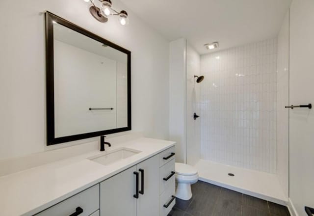 bathroom with vanity, toilet, and tiled shower