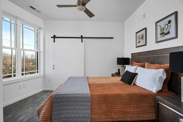 carpeted bedroom with multiple windows, a barn door, and ceiling fan