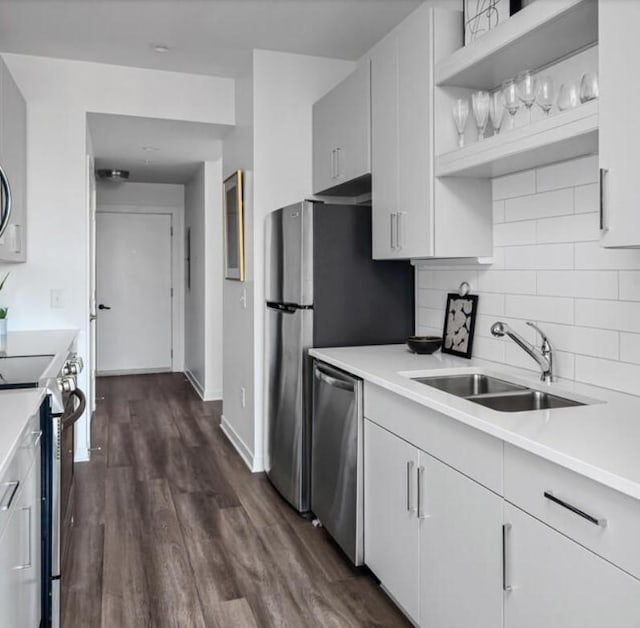 kitchen with stainless steel appliances, white cabinetry, dark wood-type flooring, and sink