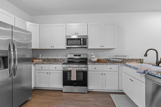 kitchen with white cabinets, appliances with stainless steel finishes, dark wood-style flooring, and a sink