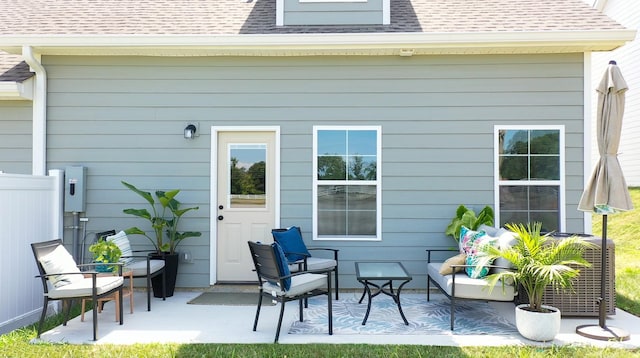 back of property with roof with shingles, a patio, and an outdoor living space