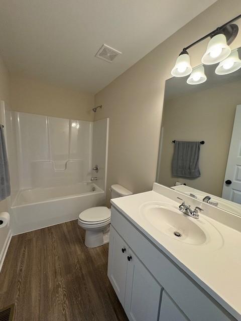 full bathroom with wood-type flooring, shower / tub combination, vanity, and toilet