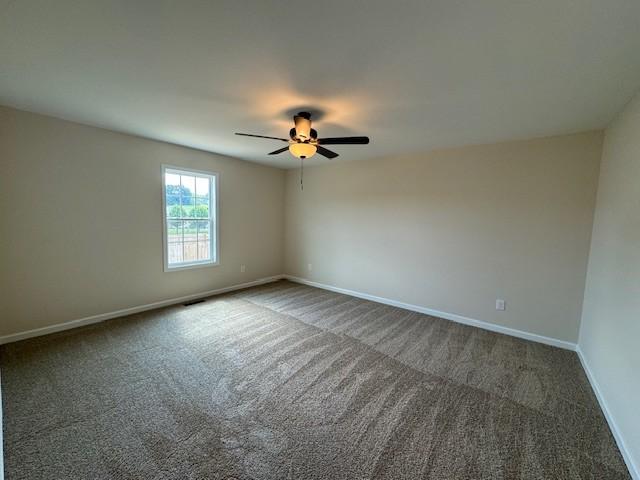 carpeted spare room with ceiling fan