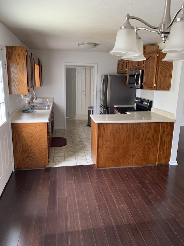 kitchen with appliances with stainless steel finishes, wood-type flooring, kitchen peninsula, and sink