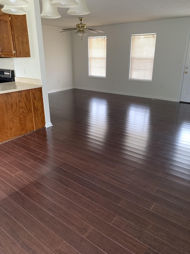 unfurnished living room featuring ceiling fan and dark wood-type flooring