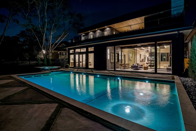 pool at twilight featuring a patio and a hot tub