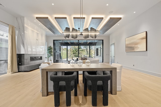 dining room with light wood-type flooring and a tiled fireplace