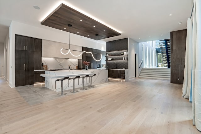 kitchen featuring pendant lighting, a breakfast bar, decorative backsplash, a kitchen island, and light wood-type flooring