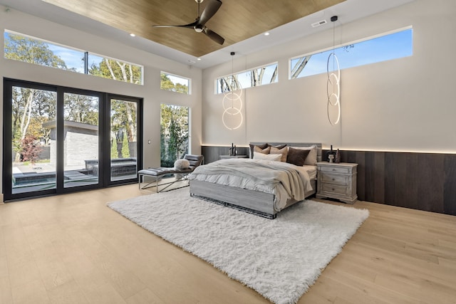 bedroom featuring wooden ceiling, light wood-type flooring, ceiling fan, access to exterior, and a high ceiling