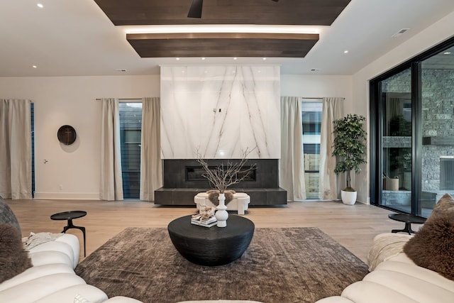 living room with a high end fireplace and light wood-type flooring