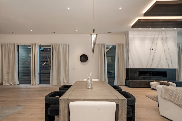 dining area featuring a tiled fireplace and light hardwood / wood-style floors