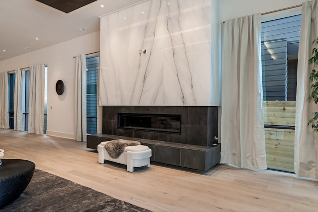 living room featuring a tile fireplace and light hardwood / wood-style flooring