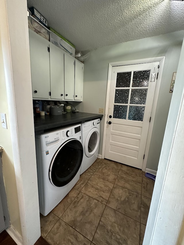 laundry room featuring cabinets, a textured ceiling, washing machine and dryer, and dark tile patterned flooring